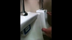 two slim dicks getting wanked at the urinals